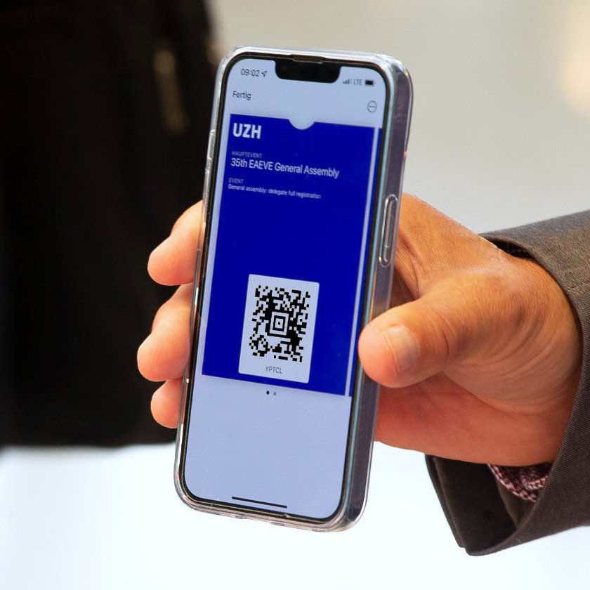 A person holds a smartphone with a QR code in their hand and shows it when checking in for an event.